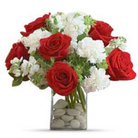 Red roses and white carnations with greens arranged in a glass vase