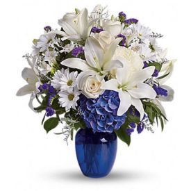 beautiful bouquet pairs pure white flowers with deep blue blooms in a gorgeous blue glass vase.